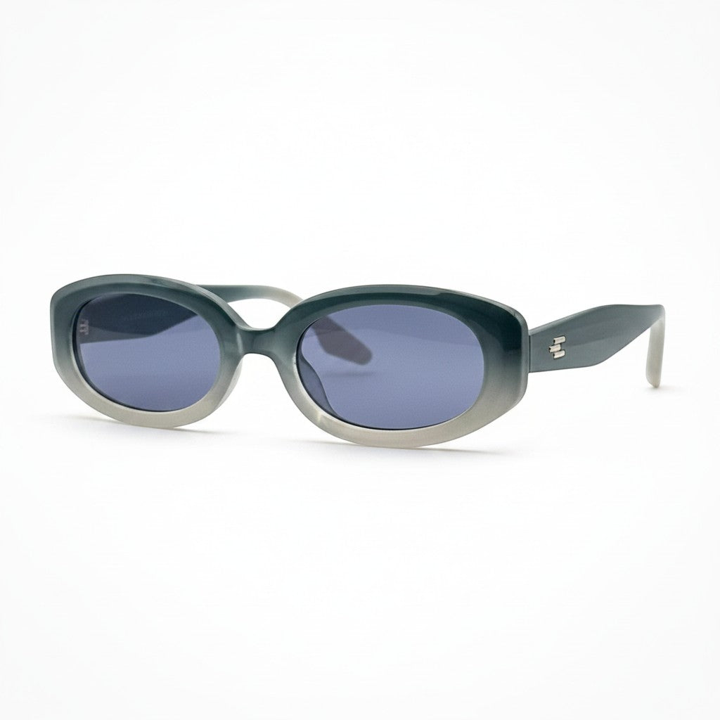 Gafas de sol Moodi Alice ovaladas en acetato gris degradado con lentes tintadas azules y detalle de logo en la patilla.